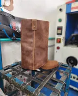 Bota de cuero marrón con diseño 2 en 1, que incluye una polaina desmontable. Presenta una caña alta estructurada y una base de bota tipo botineta con suela plana de goma negra.