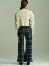 Pantalón de tiro alto con corte ancho y recto, confeccionado en tela de algodón con estampado de cuadros escoceses en tonos azul marino, verde y rojo. Presenta cierre frontal oculto con botones internos y pasacintos en la cintura.