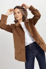Chaqueta de gamuza color tostado con cuello camisero, cierre frontal de botones y bolsillos delanteros con solapa.