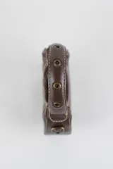 Cartera mini hobo estructurada de cuero negro, decorada con arandelas metálicas doradas en toda la superficie. Cuenta con asa corta de mano y correa de cadena metálica extraíble.