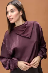 Blusa de tela satinada color bordó, con cuello drapeado amplio y mangas largas con puños elásticos.