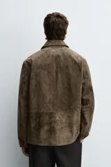 Sobrecamisa de corte regular confeccionada en piel con acabado serraje. Presenta cuello solapa, cierre frontal con botones y bolsillos de plastrón en el pecho y la parte inferior.