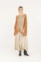 Poncho amplio de punto calado en mezcla de algodón y acrílico, con mangas regulables con jareta, degradé hecho a mano con aerógrafo, escote redondo, silueta oversize y largo a la cadera.