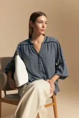 Camisa de manga larga con silueta relajada, estampado a rayas verticales en blanco y gris, escote abierto con botones frontales y puños elastizados.