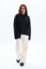 Buzo de tejido de punto color negro, con cuello redondo ajustado y mangas anchas.