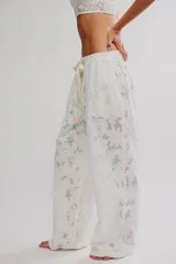 Pantalón blanco de algodón con diseño de bordados tipo broderie con motivos florales, corte holgado de pierna ancha, tiro medio con cintura elástica y cordón ajustable.