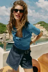 Falda pantalón cruzada de denim en color celeste, con diseño cruzado al frente, cierre frontal oculto y hebilla decorativa redonda en la cintura.