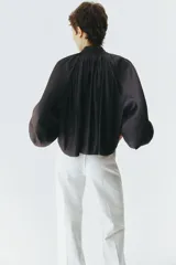 Pantalón de jean color crudo, de corte wide leg y tiro alto. Presenta cierre frontal con doble botón metálico y pliegues marcados en la parte delantera.