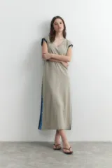 Vestido largo verde oliva con escote en V, sin mangas y detalle de botones a presión en los laterales.