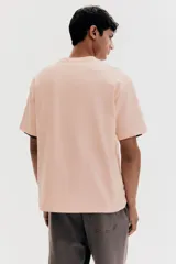 Remera color salmón de corte holgado, cuello redondo y mangas cortas.