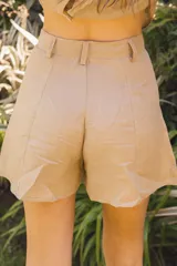 Short negro de tiro alto, con pinzas frontales y calce amplio. Presenta cierre y botón forrado en el frente.