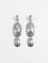 Aros largos plateados con tres dijes circulares texturizados de diferentes tamaños.