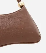 Cartera baguette marrón con textura croco, confeccionada en material sintético. Tiene cierre de cremallera y correa de hombro con esferas doradas.