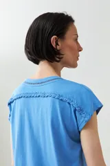 Remera color durazno con cuello en V y detalle de trenza en el escote.