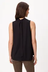 Blusa sin mangas color crema, con cuello alto fruncido y diseño holgado.