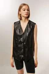 Chaleco negro de cuero sintético con cuello en V, sin mangas y corte holgado.