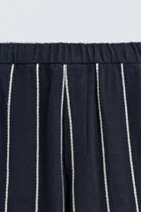 Pantalón de corte relajado, color azul marino, con rayas verticales blancas finas. Presenta cintura elástica ajustable con cordón interior y bolsillos laterales y traseros de plastrón.