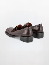 Mocasín de cuero color marrón con detalle de gamuza en la capellada, taco cuadrado y punta cuadrada.
