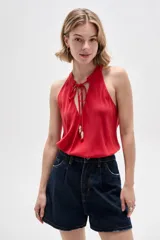 Musculosa de viscosa color rojo, con cuello halter, corte ajustado al cuerpo y detalle de cordones con cuentas en el escote.