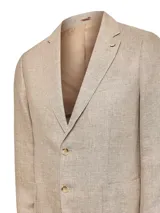 Blazer de corte regular confeccionado en lino orgánico color beige melange. Presenta cuello sastre, cierre frontal de dos botones, tres bolsillos frontales y un prendedor de madera en la solapa.