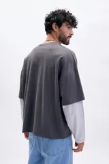 Remera de manga corta gris oscuro con cuello redondo y estampado frontal "EXCLUSIVE ARCHIVE" en blanco. Presenta un efecto de doble manga con una capa inferior de manga larga en color gris claro.