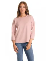 Buzo de punto de alta densidad con tacto aterciopelado, color rosa. Presenta escote a la base, mangas tres cuartos y hombros caídos. Su diseño es minimalista, con calce recto y holgado, y cuenta con pequeños tajos laterales en el ruedo.
