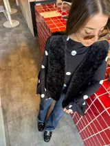 Blusa negra con estampado de lunares blancos, de corte ajustado al cuerpo, cuello redondo y mangas largas con terminación acampanada.