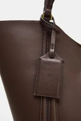 Bolso de hombro tipo maxi shopper, color beige claro, con pespuntes verticales en el cuerpo y doble asa. Incluye un bolso interior con cierre de cremallera metálica y cierre principal imantado.