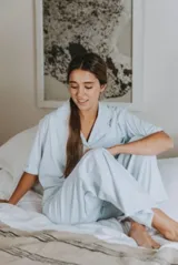 Conjunto de pijama azul a rayas blancas, compuesto por camisa de manga corta con botones y pantalón largo de corte amplio.