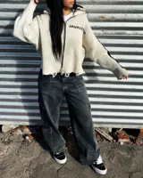 Sweater de punto color blanco con diseño gráfico negro en la espalda, cuello alto y detalles desgastados en los bordes.