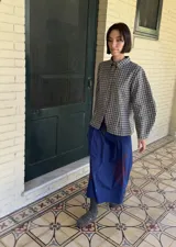 Sobrecamisa de paño con estampado de cuadros vichy en blanco y negro, de corte entallado, cuello clásico, cierre frontal con broches metálicos y mangas abullonadas.