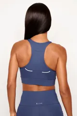 Top deportivo de alto rendimiento con diseño de espalda nadador, confeccionado en tejido técnico con protección UV50+. Presenta un bolsillo interno en el forro frontal y detalles reflectivos.