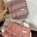 Pashmina rectangular con diseño a cuadros en tonos rosa y gris, con flecos en los bordes.