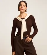 Suéter de punto acanalado color beige, con cuello redondo y mangas largas. Confeccionado en tejido tricot con textura suave y ajuste al cuerpo.