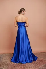 Vestido largo de fiesta color azul eléctrico, strapless, con escote corazón y detalle de piedras brillantes en el borde superior. Tiene corte imperio con falda amplia y plisada.