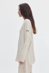 Buzo negro de tejido de ochos, con cuello redondo y diseño oversized de corte largo y amplio con tajos laterales.