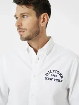 Camisa blanca de corte regular y manga larga, con logo bordado en el pecho y botón a contraste.