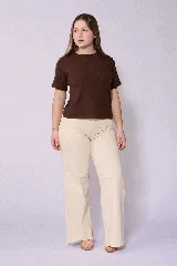 Jean de corte wide leg en color beige, con tiro alto y cierre frontal con botón y cremallera. Presenta un diseño de cinco bolsillos y costuras reforzadas.