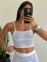 Conjunto deportivo lila compuesto por un top corto con tirantes finos y una minifalda con short incorporado.