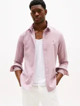Camisa de hombre Tommy Hilfiger de manga larga, color rosa, confeccionada en algodón regenerativo de tejido dobby. Tiene cuello camisero clásico, cierre con botones, puños abotonados y logo de Tommy Hilfiger bordado en el pecho.
