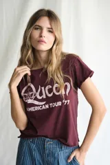 Remera de manga corta color bordó oscuro, con cuello redondo y dobladillos deshilachados en mangas y ruedo. Estampado frontal en blanco con el logo de la banda Queen y el texto "AMERICAN TOUR '77".