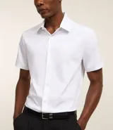 Camisa de manga corta con cuello inglés y cierre frontal abotonado, confeccionada en una mezcla de fibras de bambú, viscosa, poliéster y elastano. Presenta un diseño liso y entallado.
