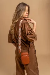 Bandolera compacta color rojo con textura de cuero, correa regulable y desmontable con diseño de rayas rojas y blancas. Cuenta con bolsillos frontales y cierre, interior forrado en tela.