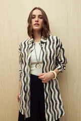 Vestido camisero de corte relajado con estampado de ondas verticales en tonos neutros. Presenta cuello clásico, cierre frontal con botones y mangas largas. Confeccionado en tejido fluido con caída liviana.