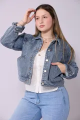 Campera de jean de mujer, color azul claro lavado, con corte cropped y estilo clásico. Presenta cuello camisero, botones metálicos frontales y bolsillos de parche en el pecho.