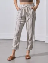 Pantalón de lino color beige con rayas verticales grises, corte recto, cintura alta con cordón ajustable y bolsillos laterales.