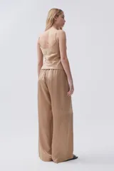 Pantalón palazzo color beige de viscosa, tiro alto, con bolsillos laterales y pinzas en el frente.