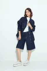 Sobrecamisa de denim azul oscuro con diseño de rayas verticales blancas, corte oversize, cuello clásico, cierre frontal con botones y bolsillos delanteros.