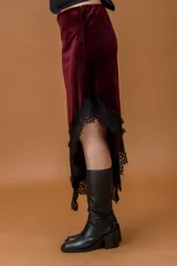 Falda midi confeccionada en terciopelo negro, con corte irregular y terminación de encaje en el ruedo.