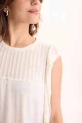 Blusa de viscosa negra sin mangas, con diseño fluido, cuello redondo y detalles de tablas verticales en el pecho con terminaciones de encaje en las sisas.